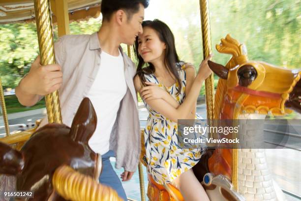 young lovers riding merry rides on the playground - carousel musical fotografías e imágenes de stock