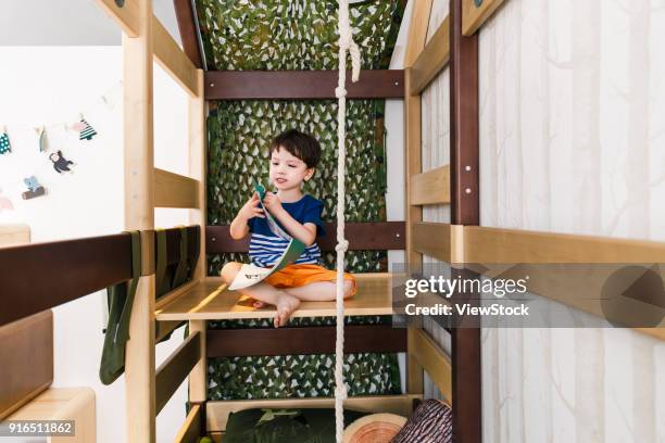 lovely boy reading in the bedroom - bunk beds for 3 stock-fotos und bilder