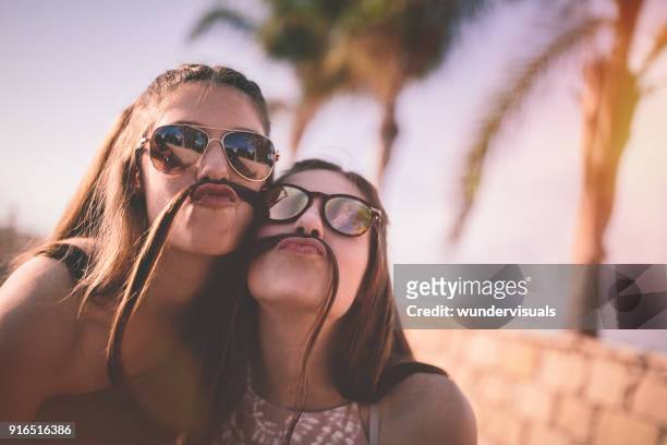 tienermeisjes worden zot maken van grappige gezichten met haar snorren - silly girl stockfoto's en -beelden