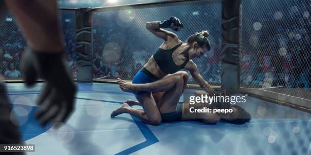 luchadores de artes marciales mixtas femeninas lidiando en octágono durante la competición - mixed martial arts fotografías e imágenes de stock