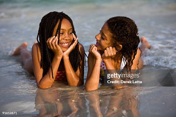sisters lying on the water on the beach - derek latta stock-fotos und bilder