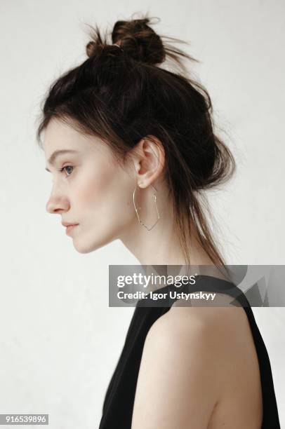 close-up profile of pensive young woman looking away - messy bun stockfoto's en -beelden