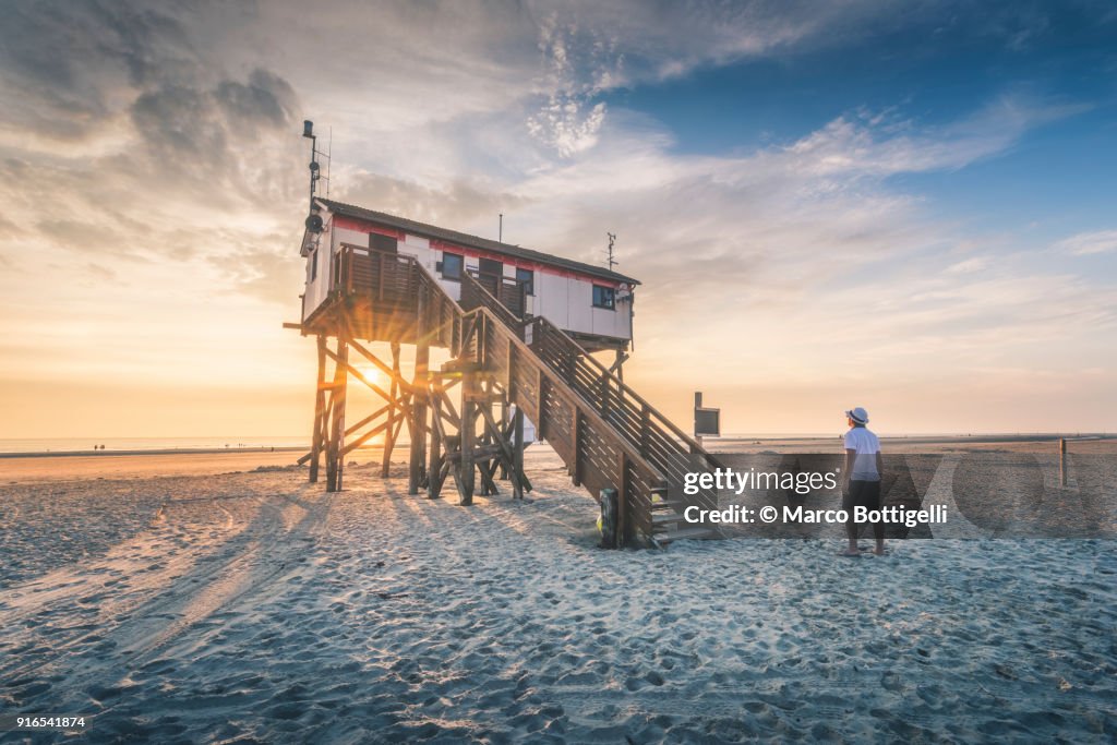 Tourist watching a stilt house on the wadden sea, Germany.