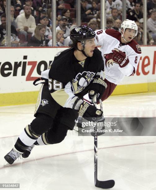 Kris Letang of the Pittsburgh Penguins looks to pass as Scottie Upshall of the Phoenix Coyotes trails the play at Mellon Arena on October 07, 2009 in...