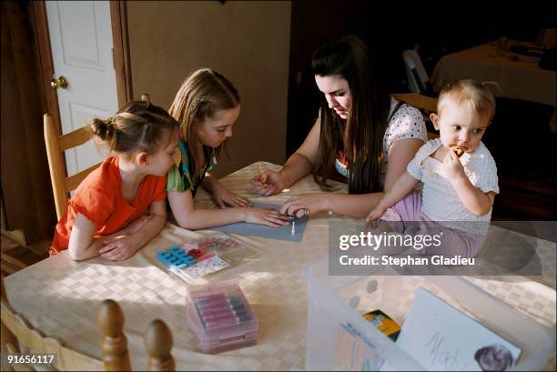 Laura helps her 9-year-old sister Madison paint her nails while 6-year-old Kyley is watching. Two-year-old Angelina sits on the table. In this...