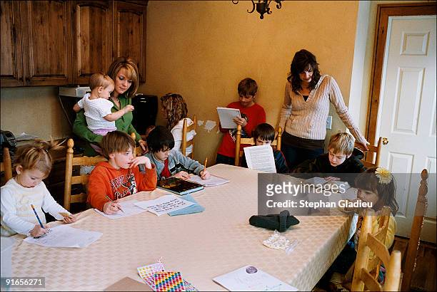 Valerie and Allie are helping some of their children with their homework. This polygamist family consisting of three mothers, one father and 21...