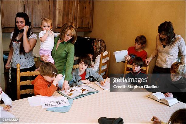 Valerie and Allie are helping some of their children with their homework. This polygamist family consisting of three mothers, one father and 21...