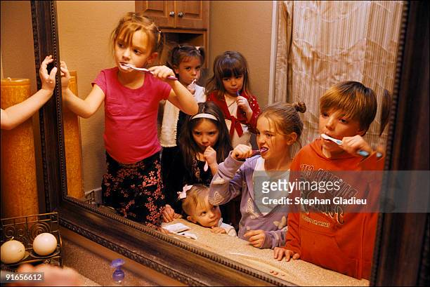 Seven of the 21 children of a polygamist family brush their teeth in one of the five bathrooms of the house they share with their father and three...