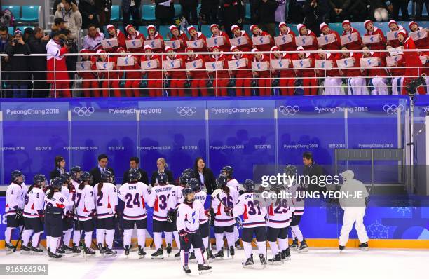 North Korea's cheerleaders hold the Unified Korea flag and cheer after the women's preliminary round ice hockey match between Switzerland and the...