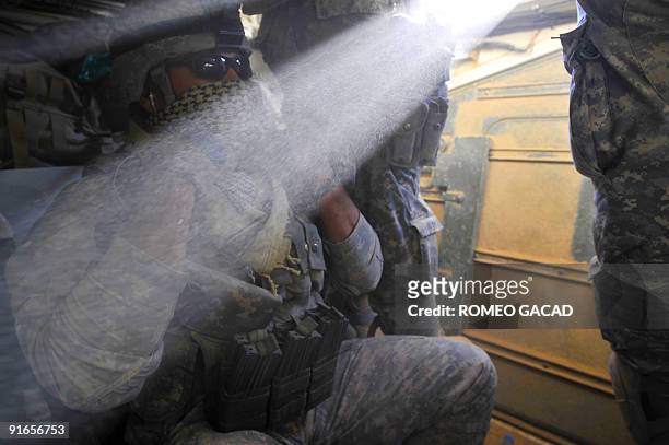Army Sergeant Christian Fuentes covers his face as thick dust blows inside the armored Stryker vehicle of the 3rd Platoon of Charlie Company, 1st...