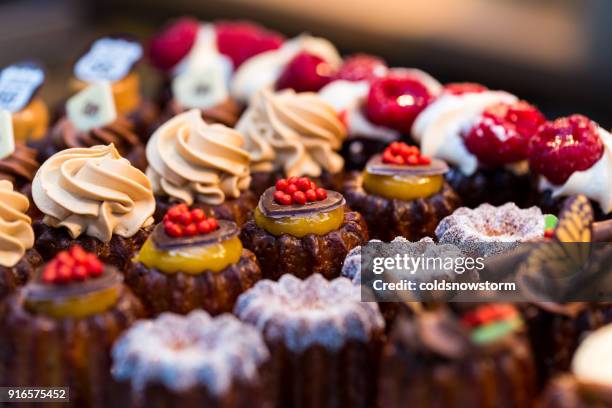 nahaufnahme von frisch gebackenem kuchen und cupcakes in folge auf lebensmittelmarkt - obstauslage stock-fotos und bilder