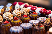 Close up of freshly baked cakes and cupcakes in a row at food market