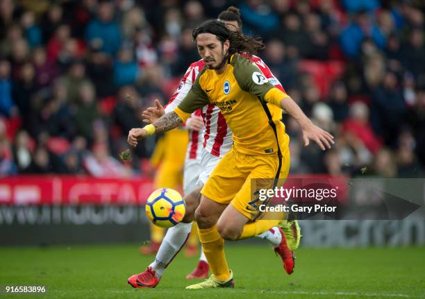 Matias Ezequiel Schelotto of Brighton and Hove Albion runs with the ball under pressure from Maxim Choupo-Moting of Stoke City during the Premier...