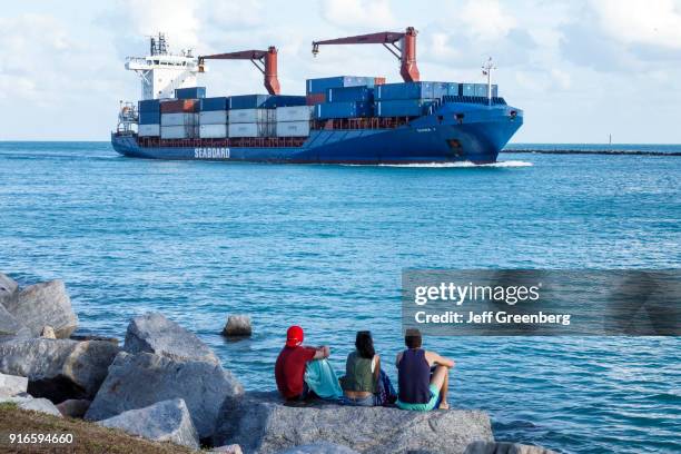 Three friends watching a cargo container ship arriving at Port of Miami.