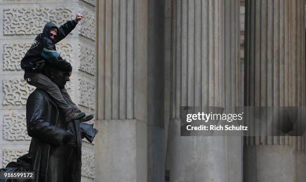 Philadelphia Eagles fan climbs onto of a statue of John Wanamaker in front of City Hall during the team's Super Bowl Victory Parade on February 8,...