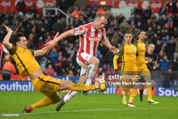 Lewis Dunk of Brighton and Hove Albion tackles Charlie Adam of Stoke City during the Premier League match between Stoke City and Brighton and Hove...