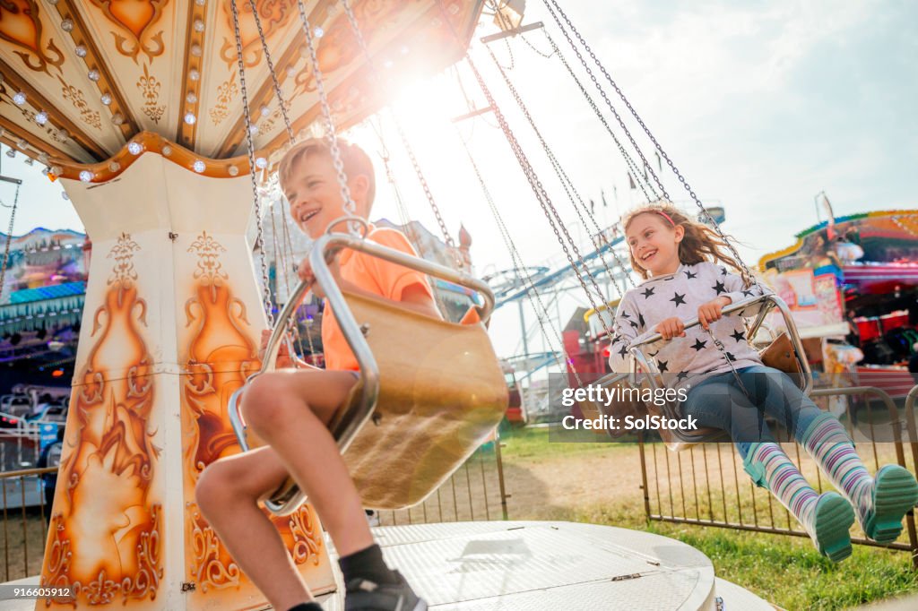 Kinderen rijden op de schommels op de kermis