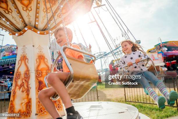 children riding on the swings at the fairground - parque de diversões edifício de entretenimento imagens e fotografias de stock