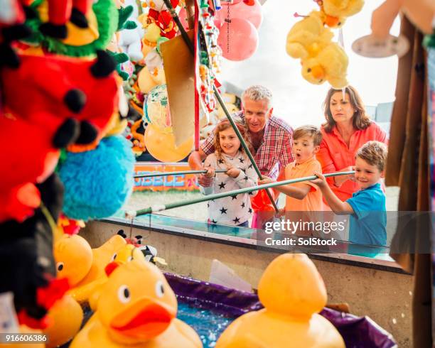 grootouders helpen hun kleinkinderen haak een eend - traveling carnival stockfoto's en -beelden