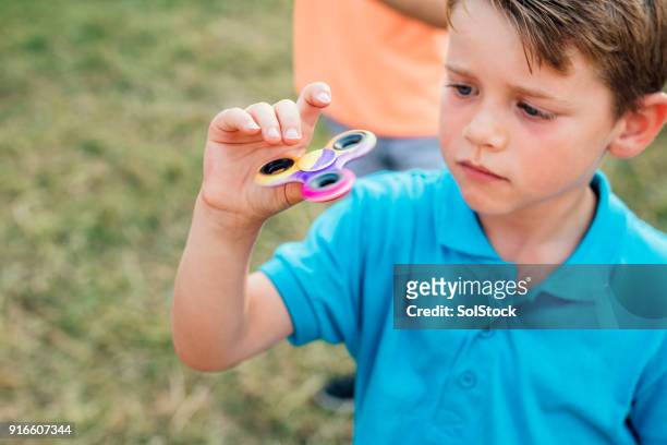 kleiner junge spielt mit einem fidget spinner - fidget spinner stock-fotos und bilder