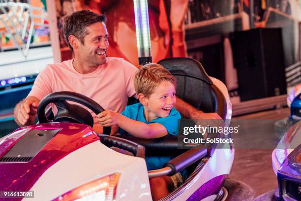 father and son driving dodgem cars - carnival of cunit stock pictures, royalty-free photos & images