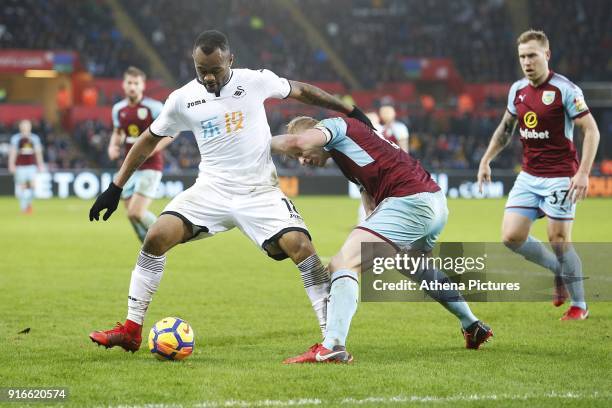 Jordan Ayew of Swansea City is challenged by Ben Mee of Burnley during the Premier League match between Swansea City and Burnley at the Liberty...