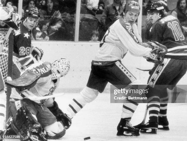 Finnish goalie, Jorma Valtonen, blocks a shot on goal by America's Mark Johnson as John Harrington comes up to try for the rebound.