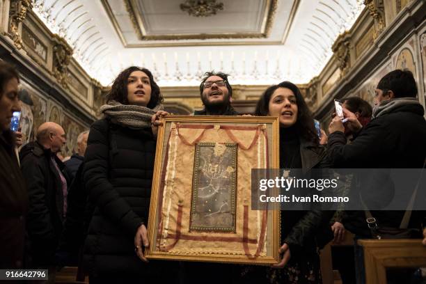 Three faithful show an ex voto representing the image of the Madonna of Montevergine inside one of the chapels of the sanctuary on February 2, 2018...