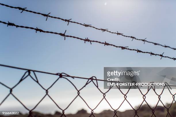 barbed wire fence on street - political uncertainty stock pictures, royalty-free photos & images