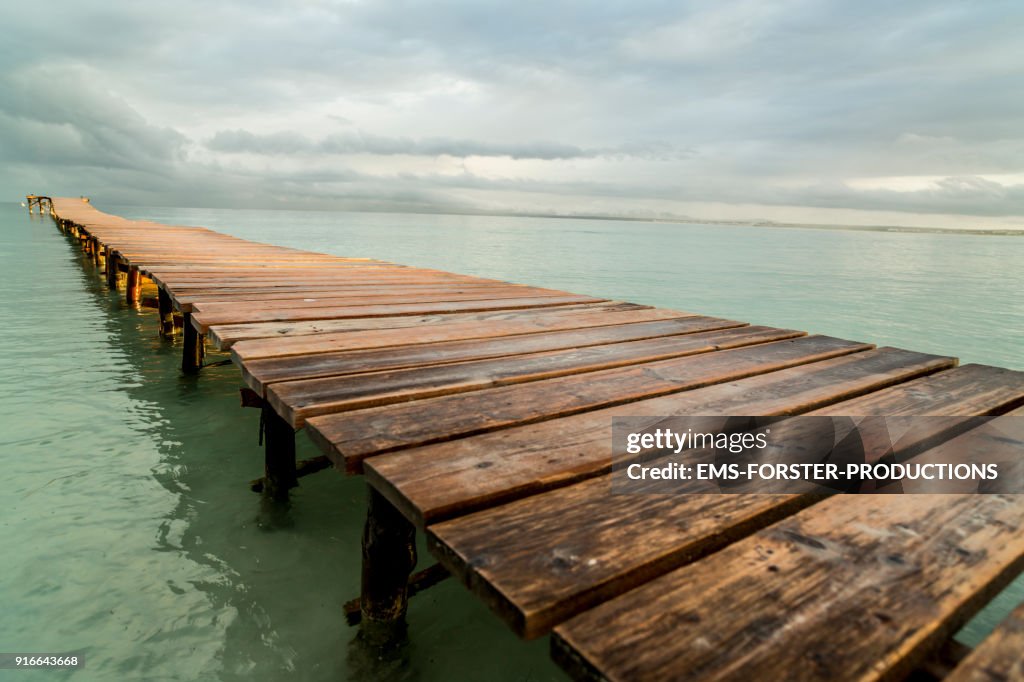 Playa de Muro with idyllic long wooden jetty in caribbean coloured waters and mountain range in background