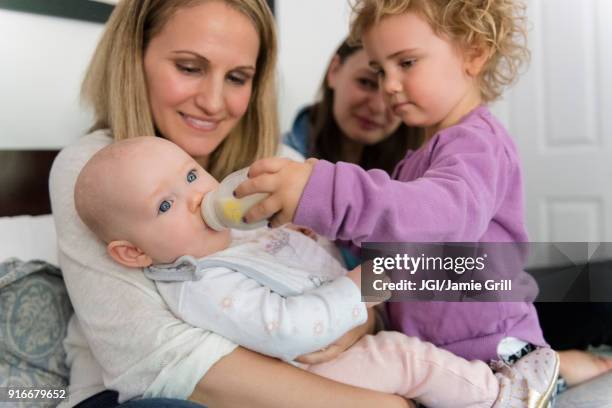 caucasian girl feeding bottle to baby sister - sisters feeding stock pictures, royalty-free photos & images
