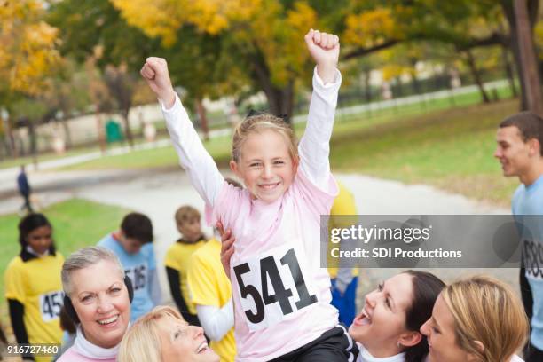 excited little girl finishes charity race - bib stock pictures, royalty-free photos & images