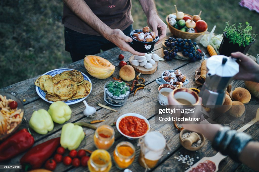 Junge Menschen, die einen Picknick im Freien, verschiedene gesunde Zubereitung auf dem alten Holztisch