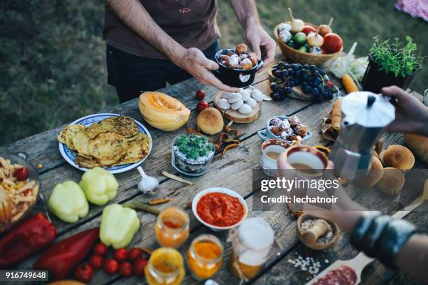 Young people having a picnic outdoors, preparing various healthy food on the old wooden table