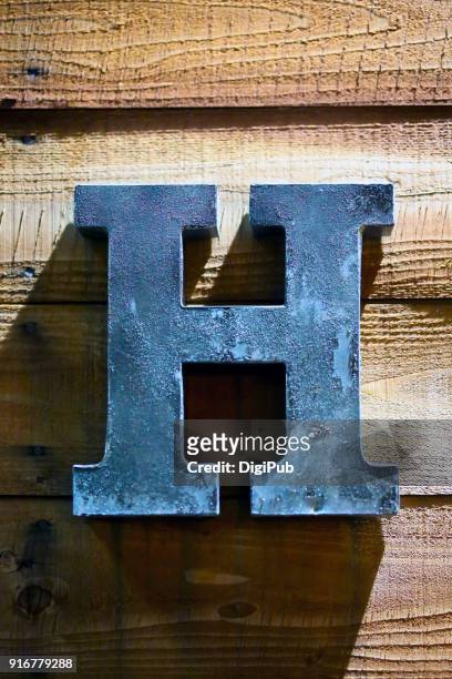 iron sheet 3d capital letter h on plank wall - h stock-fotos und bilder