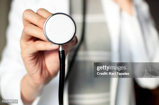 a female doctor is holding a stethoscope in her clinic - stethoskop stock-fotos und bilder