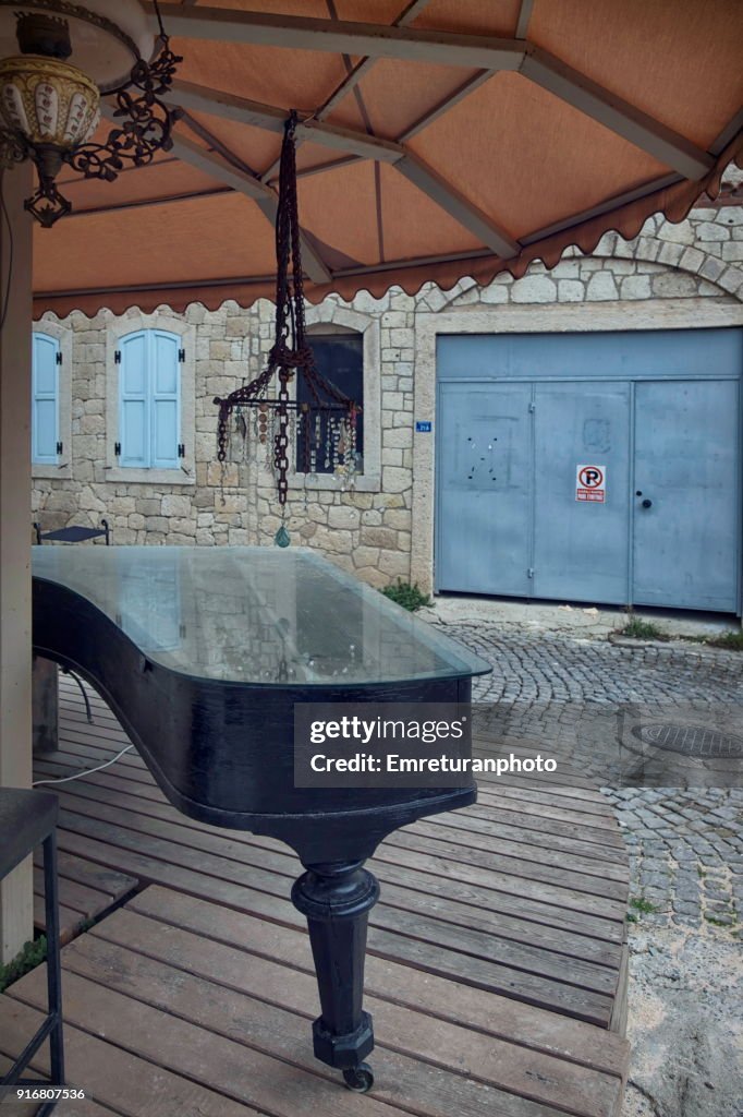 Abandoned piano outdoors under a sunshade.