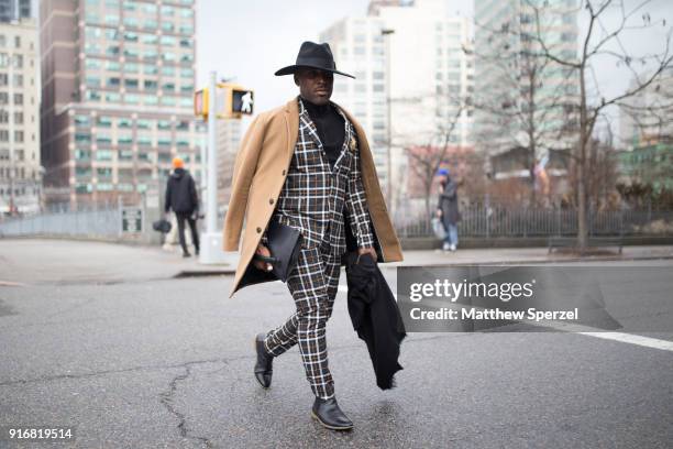 Guest is seen on the street attending Taoray Wang during New York Fashion Week wearing a camel coat with plaid suit and black cowboy hat on February...