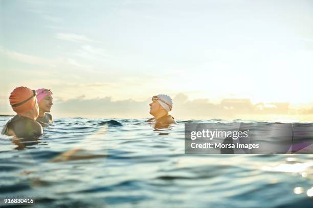 frauen reden beim schwimmen im meer bei sonnenuntergang - 3 old people stock-fotos und bilder