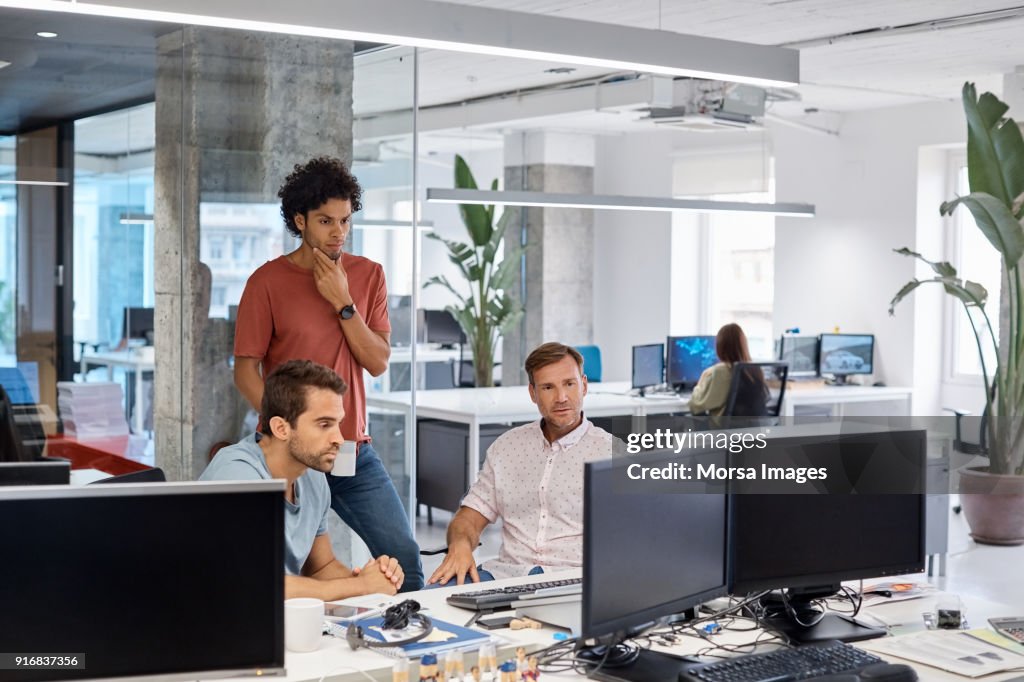 Serious businessmen looking at computer in office