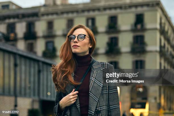 thoughtful woman wearing long coat walking in city - turtleneck stock pictures, royalty-free photos & images