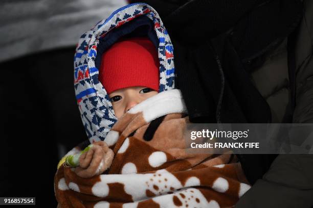 Spectator holds her baby as she waits for the start of the men's 10km sprint biathlon event during the Pyeongchang 2018 Winter Olympic Games on...