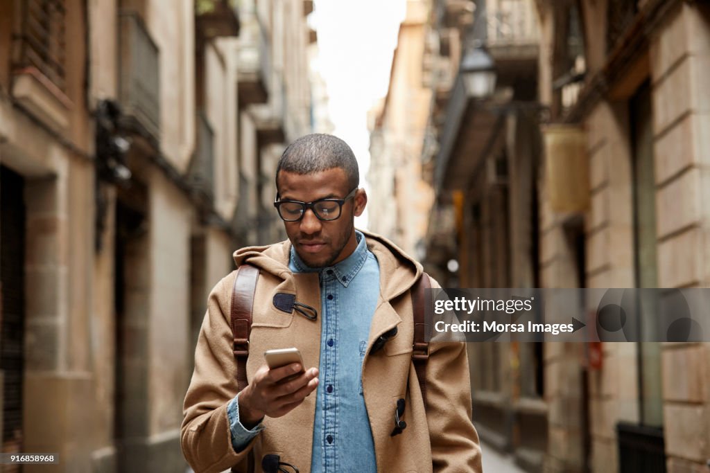 Jeune homme à l’aide de téléphone portable au milieu de bâtiments