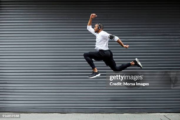 sportliche junge mann springt gegen auslöser - running midair stock-fotos und bilder