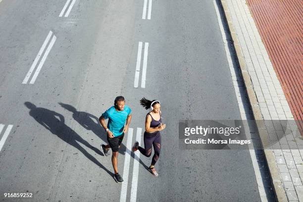 paar joggen op straat tijdens zonnige dag "n stad - forward athlete stockfoto's en -beelden