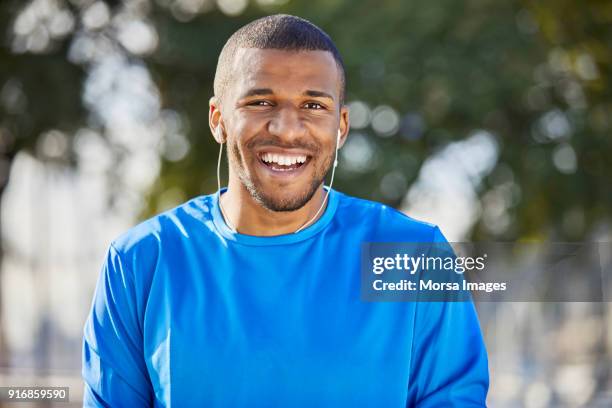 portrait of happy man with headphones at park - blue tshirt stock pictures, royalty-free photos & images