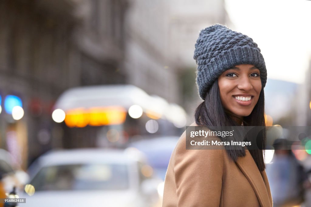 Lächelnde Frau mit Stricken Hut auf Stadtstraße