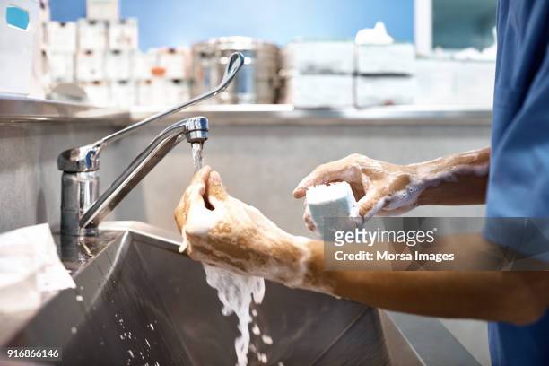 veterinarian washing hands with soap at sink - middle age imagens e fotografias de stock