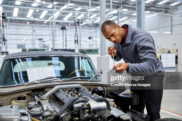 engineer checking motor oil with dipstick by car - dipstick stock pictures, royalty-free photos & images