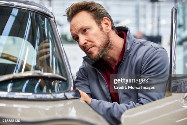 male engineer examining vintage car in industry - vintage car stock pictures, royalty-free photos & images